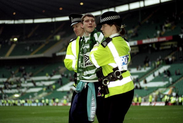 2 May 1999:  The police escort a Celtic fan out of the stadium during the Scottish Premiership match played at Celtic Park In Glasgow, Scotland. Ra...